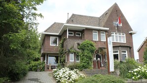 A two-story house with a brick facade, a tiled roof, and a flagpole.