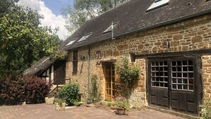 A stone building with a tiled roof, a wooden door, and a large window with a grid pattern.