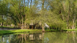 A serene lakeside scene with a wooden cabin and a small bridge.