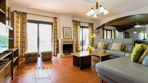 Amplia sala de estar con chimenea, un conjunto de sofás y una televisión.