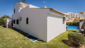Ein weißes, zweigeschossiges Haus mit kleiner angeschlossener Garage, einem Pool und einem gepflegten Rasen.