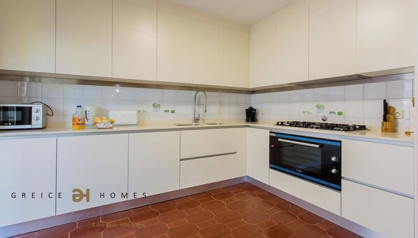 A modern kitchen with white cabinets, a Bosch oven, a microwave, and a sink. - Quinta do Romão (Quarteira)
