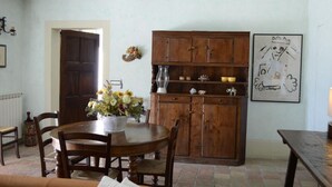 A dining area with a wooden table and chairs, a cabinet with dishes, and a framed picture on the wall. - Detached villa 50 meters from the sea (Isola d'Elba)
