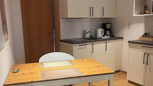 Eine kleine Küche mit einem Holztisch, weißen Stühlen und Pendelleuchten.