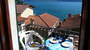 Un balcon avec une table dressée pour deux personnes, donnant sur un lac avec des montagnes en arrière-plan.