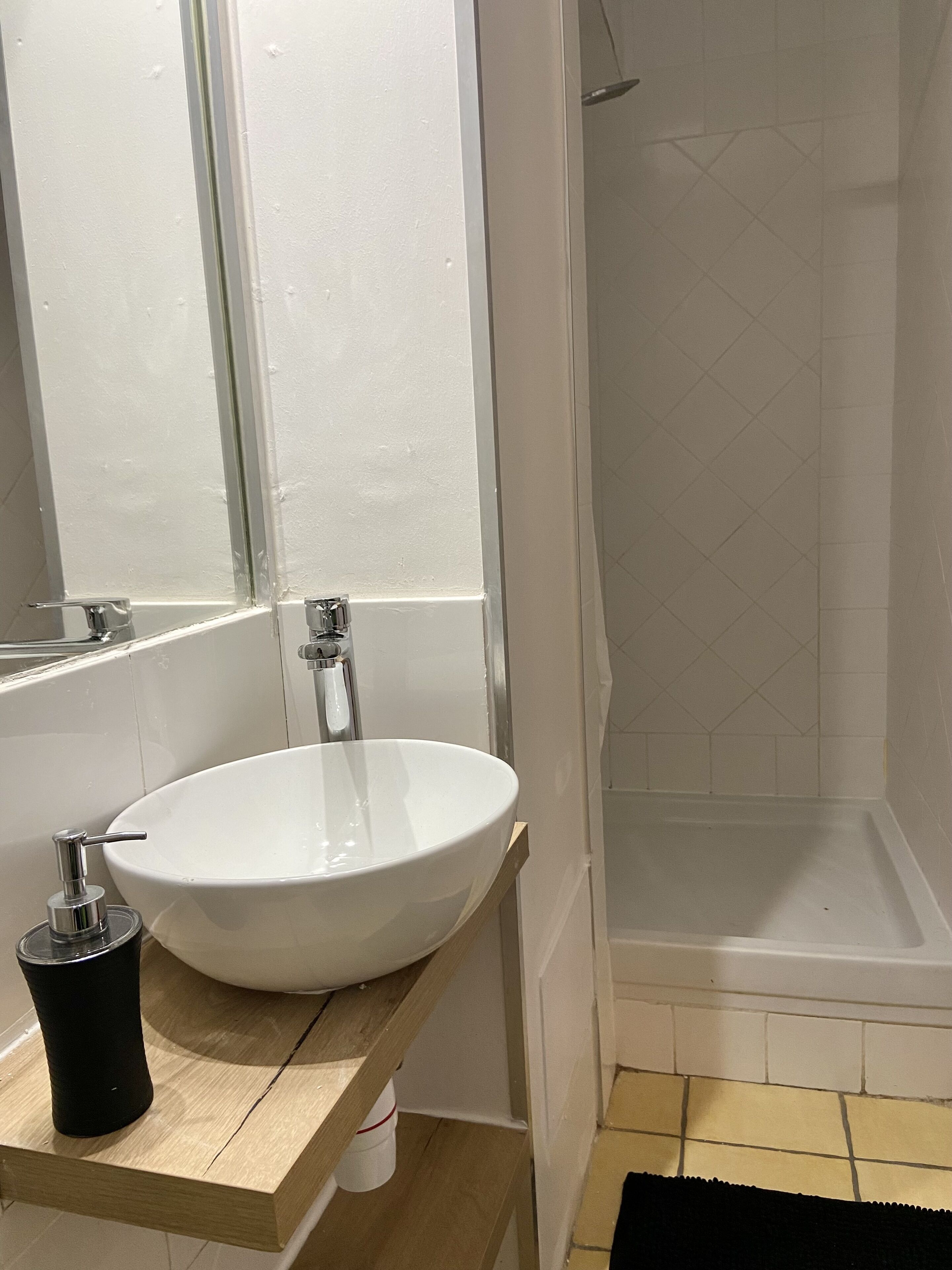 A bathroom with a white sink, a mirror, and a shower area.