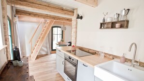 Una cocina moderna con vigas de madera, horno empotrado y encimera de madera.