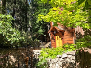 A rustic cabin with a stone wall, wooden door, and a lantern.