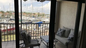 A balcony with a view of a marina, a sofa, and a chair. - GOLF  BOATING BIKING (Punta Gorda)