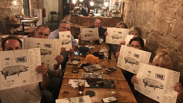 A group of people at a restaurant table with menus featuring a pig illustration, surrounded by wine glasses and cutlery. - GOLF  BOATING BIKING (Punta Gorda)