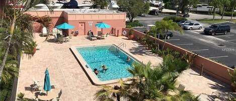 A hotel pool area with lounge chairs, umbrellas, and a swimming pool.