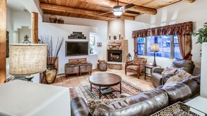 Una sala de estar acogedora con chimenea, sofá de cuero y ventilador de techo.