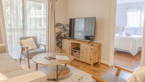 A modern living room with a sofa, armchair, coffee table, TV, and wooden cabinet. - First Floor, Updated, and a Short Walk to the Beach (Hilton Head Island)