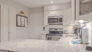 A kitchen with white cabinets, a microwave, an oven, and granite countertops. - First Floor, Updated, and a Short Walk to the Beach (Hilton Head Island)