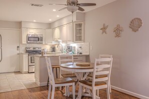 A kitchen with white cabinets, a microwave, stove, and a dining area with a round table and chairs. - First Floor, Updated, and a Short Walk to the Beach (Hilton Head Island)