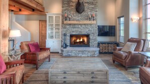 Ein gemütliches Wohnzimmer mit Kamin aus Stein, Ledersofas und einem Holztisch.