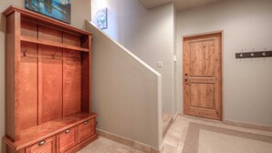 Un couloir avec un banc en bois, une porte et un escalier.