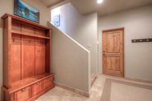 A hallway with a wooden bench, a door, and a staircase.