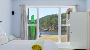 A bedroom with a bed, a window with a view of a lake and trees, and a door. - Stylish Lakefront Home - Last Minute Getaway for the Summer (Hot Springs)