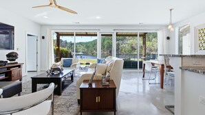 A modern living room with a sofa, coffee table, and a dining area with chairs. - Stylish Lakefront Home - Last Minute Getaway for the Summer (Hot Springs)