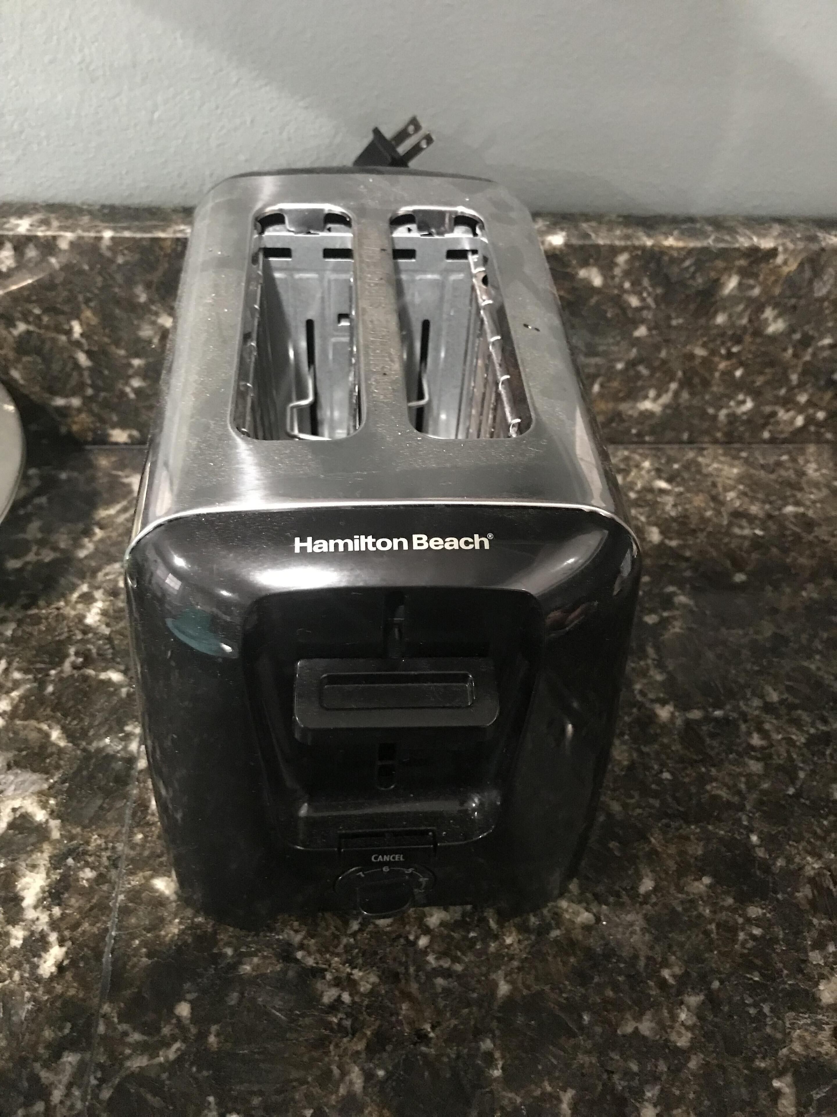 A kitchen with a black toaster on a granite countertop.