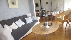 Una sala de estar con un sofá, una mesa redonda de madera y un comedor con mesa y sillas.