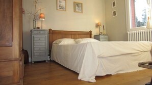 Un dormitorio con una cama de madera, dos mesitas de noche con lámparas, un aparador y una ventana con vistas.
