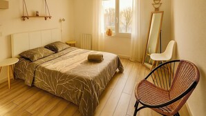 Une chambre à coucher avec un lit, une chaise, un miroir et une fenêtre avec des rideaux.
