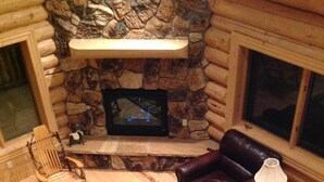 A log cabin interior with a stone fireplace, leather furniture, and a television. - Spectacular Family-Friendly Log Cabin Style Home Near Grand Lake /Rocky Mtn NP! (Grand Lake)
