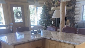 A kitchen with a granite countertop, wooden cabinets, and a stone wall. - Spectacular Family-Friendly Log Cabin Style Home Near Grand Lake /Rocky Mtn NP! (Grand Lake)