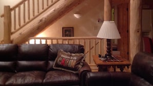A cozy cabin interior with a wooden staircase, leather sofas, and a lamp on a wooden table. - Spectacular Family-Friendly Log Cabin Style Home Near Grand Lake /Rocky Mtn NP! (Grand Lake)
