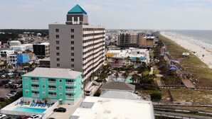 A coastal hotel with multiple floors, a rooftop pool, and a beach view. - ☀ Breezy, Open Condo, Steps from Beach and Boardwalk with Ocean Views & Pool ☀  (Carolina Beach)