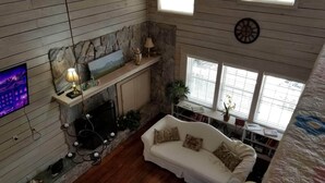 Una sala de estar acogedora con chimenea, un sofá, un televisor y una estantería.