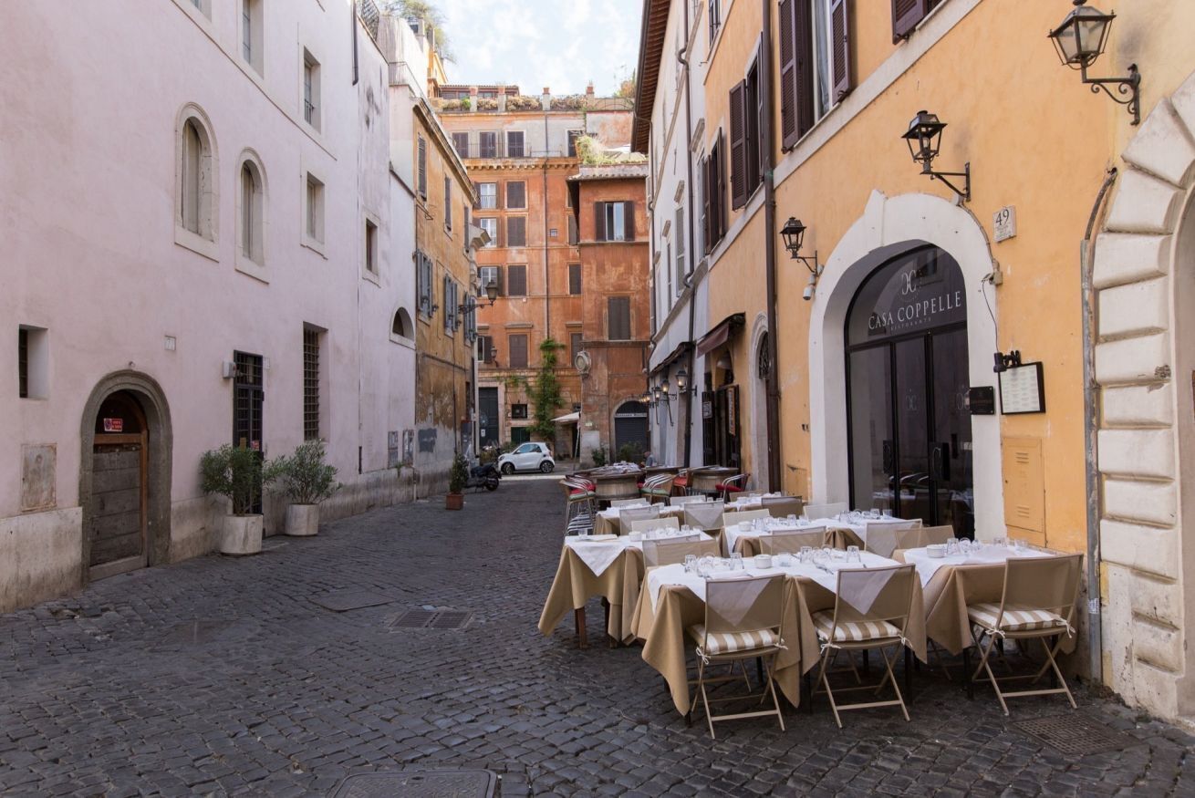 Una calle adoquinada con mesas y sillas en una terraza de restaurante.