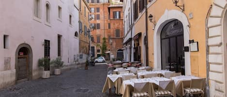 Una calle adoquinada con mesas y sillas en una terraza de restaurante.