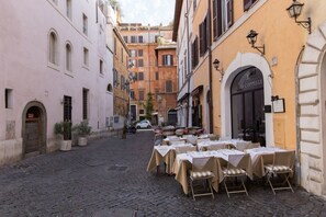 Una strada acciottolata con tavolini all'aperto di un ristorante.
