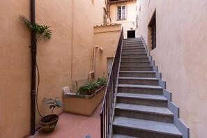 Eine schmale Treppe, links ein Blumentopf und rechts ein kleiner Pflanzkasten mit Pflanzen.