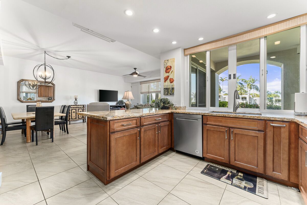 A modern kitchen with wooden cabinets, a dishwasher, and a dining area with a table and chairs.