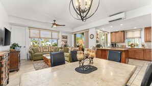 A spacious living area with a large dining table, comfortable seating, and a ceiling fan. - #1301 Ocean Views, 1st Floor, Best location, Courtyard, Great Promotion (Kihei)