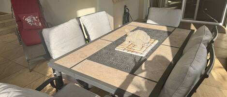 A dining table with a decorative tile centerpiece, surrounded by cushioned chairs.