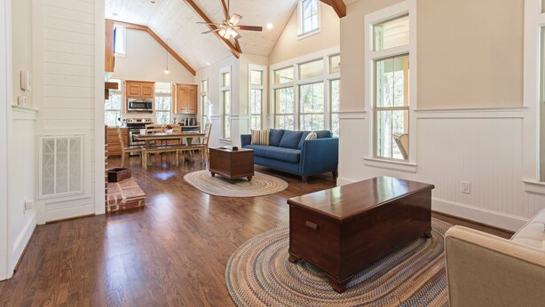 Un salon spacieux doté de planchers en bois franc, d’un canapé bleu, d’une table basse en bois et d’un ventilateur de plafond.