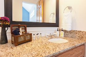 Bathroom features a granite countertop, large mirror, and a bathtub.