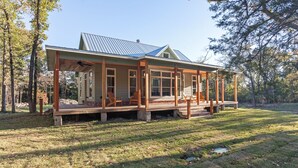 Une maison dotée d’un porche abrité, de grandes fenêtres et d’un toit en métal.
