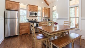 Une cuisine spacieuse, dotée d’armoires en bois, d’appareils électroménagers en acier inoxydable et d’une grande table à manger.
