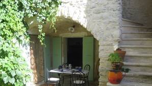 An outdoor dining area with a stone wall, a table with chairs, and a potted plant. - COTTAGE WITH HEATED POOL - MAS IN THE GARRIGUE D'UZES (Fons-Sur-Lussan)