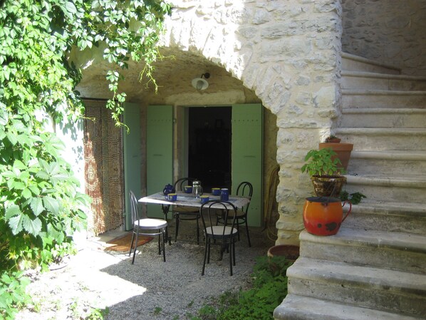 Un área de comedor al aire libre con una pared de piedra, una mesa con sillas y una planta en maceta.