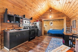 A cozy cabin interior with a kitchen, dining area, and a bed. - Cozy Cabin for 2 in the Heart of RRG! (Campton)