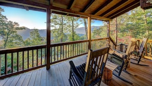Eine Holzterrasse mit Blick auf einen Wald und Berge.