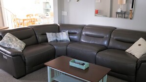 A brown leather sectional sofa with two pillows, a wooden coffee table, and a light blue tray table. - Adjacent to beaches, 3 minute walk to downtown, Quiet Atmosphere, FREE WIFI (Sodus Point)