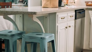 A kitchen with white cabinets, a countertop, and two blue stools. - Adjacent to beaches, 3 minute walk to downtown, Quiet Atmosphere, FREE WIFI (Sodus Point)